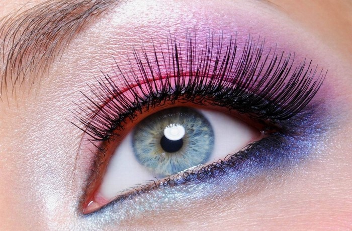 Close-up of a blue eye with pink and purple eyeshadow and false eyelashes
