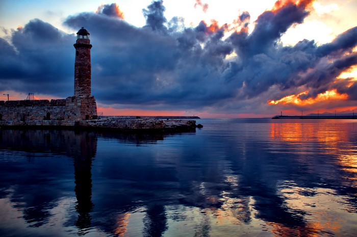 Lighthouse at sunset with dramatic clouds over the sea