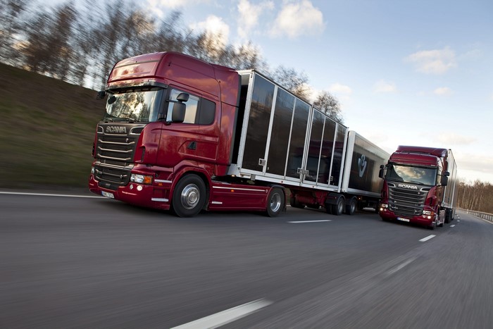 Two red Scania trucks driving on a highway