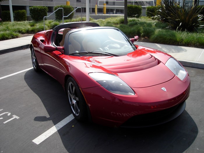 Red Tesla Roadster parked in a parking lot