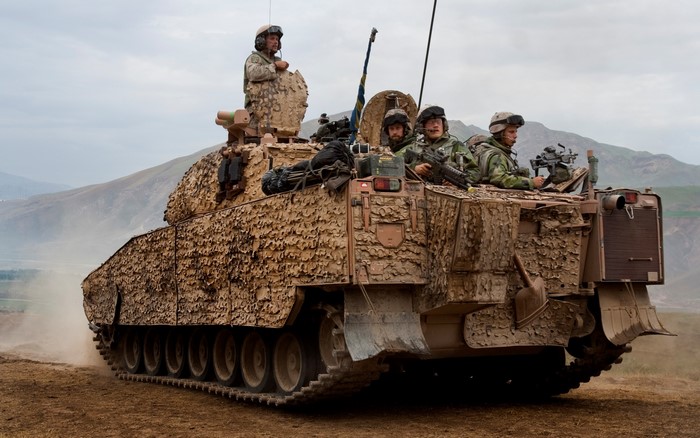 Soldiers on an armored personnel carrier in a mountainous landscape