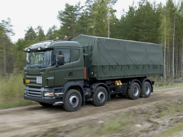 Green Scania military truck driving on a dirt road
