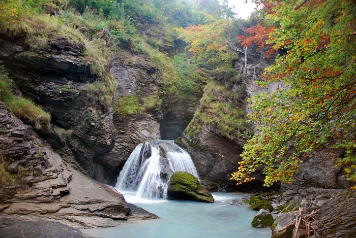 Waterfall cascading into a turquoise pool surrounded by rocks and trees