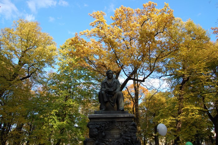 Statue of a man in a park with autumn trees in St. Petersburg
