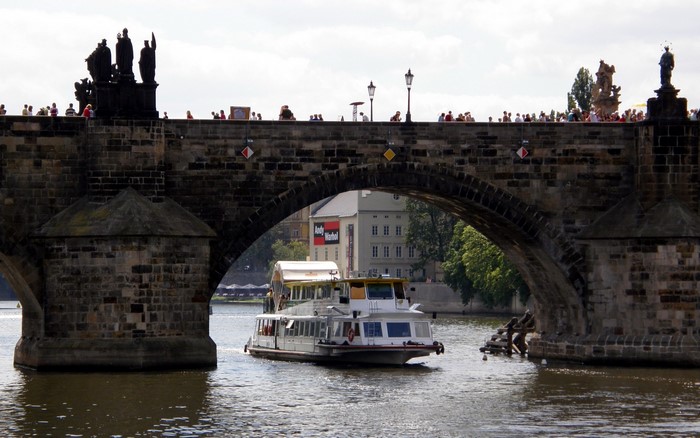 Charles Bridge with Riverboat in Prague, Czech Republic