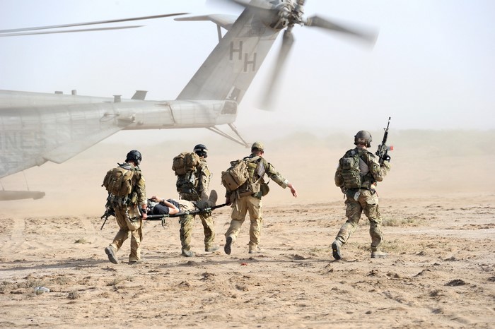 Soldiers carrying a casualty on a stretcher near a helicopter
