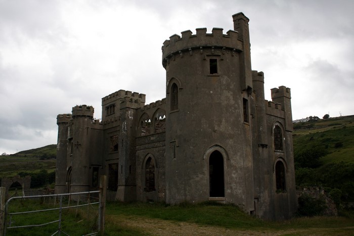 Ruined castle on a grassy hill under a cloudy sky