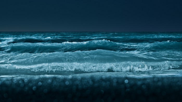 Ocean waves crashing on the shore at night