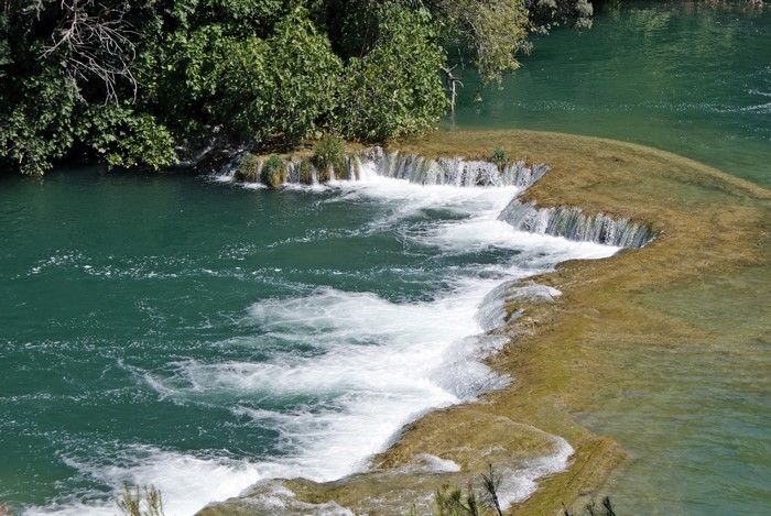 Waterfalls and lush green trees by a river