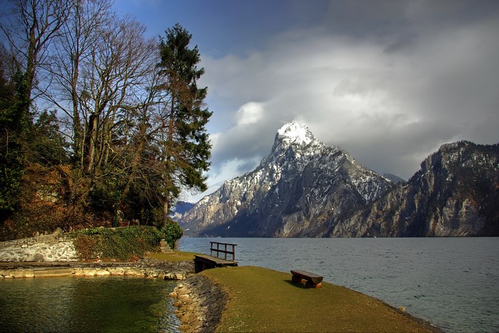 Lake and snow-capped mountain with trees and bench