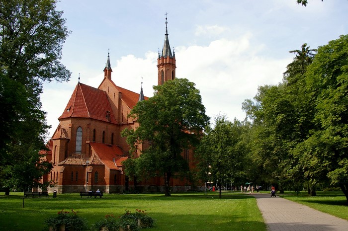 Brick church with red roof and spires in a park
