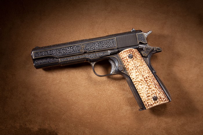Engraved Colt 1911 pistol with ivory grips