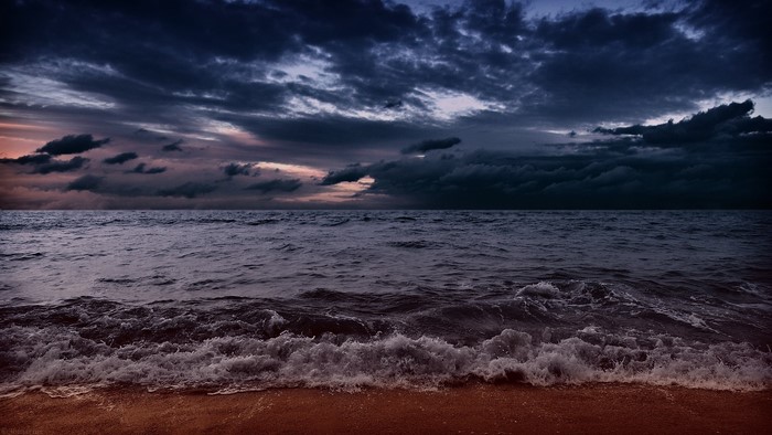 Dark stormy clouds over the ocean and beach