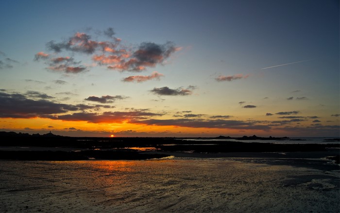 Sunset over a rocky coastline with clouds