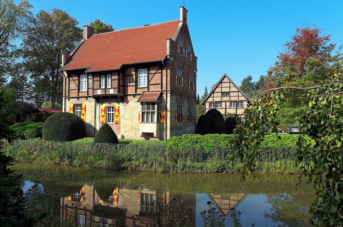 Half-timbered house with red roof reflected in water