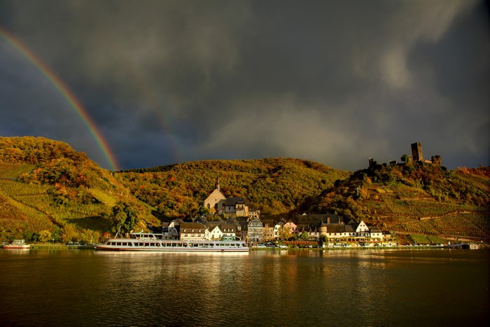 River cruise ship passing a village with a castle in Germany