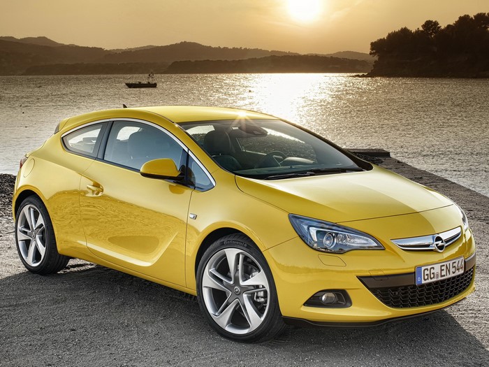 Yellow Opel Astra parked by the water at sunset