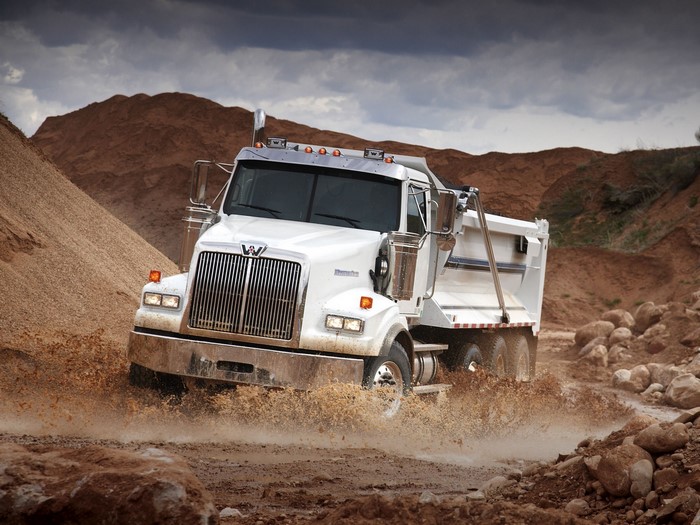 White Western Star dump truck driving through mud