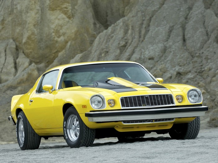 Yellow Chevrolet Camaro parked on gravel