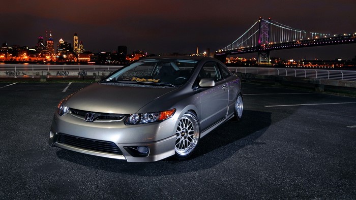 Honda Civic Coupe parked at night with city skyline and bridge