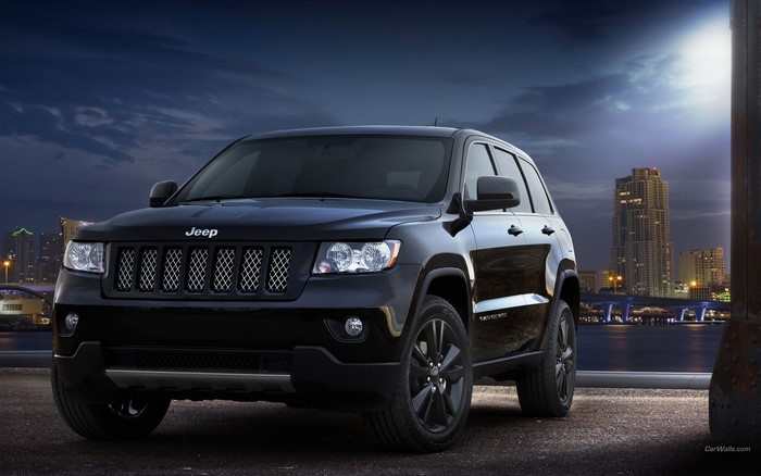 Black Jeep Grand Cherokee parked at night with city skyline