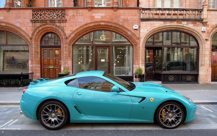 Turquoise Ferrari parked in front of a building