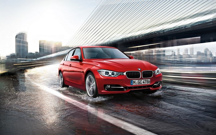 Red BMW driving through water in a city