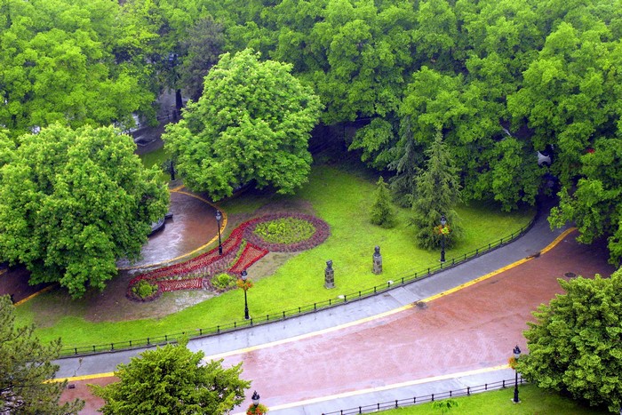 A park with trees, flower beds, and a path