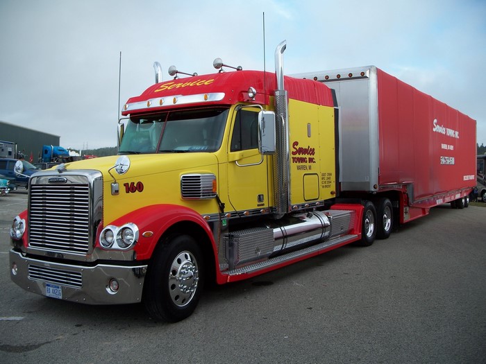 Yellow and red Freightliner towing truck with trailer