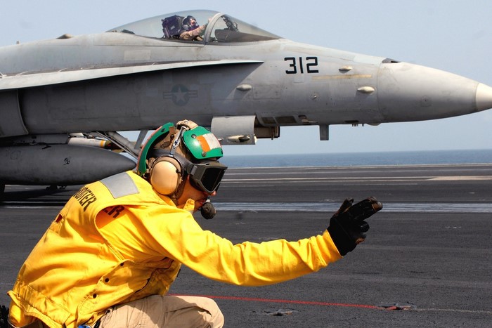 Fighter jet on aircraft carrier with deck crew