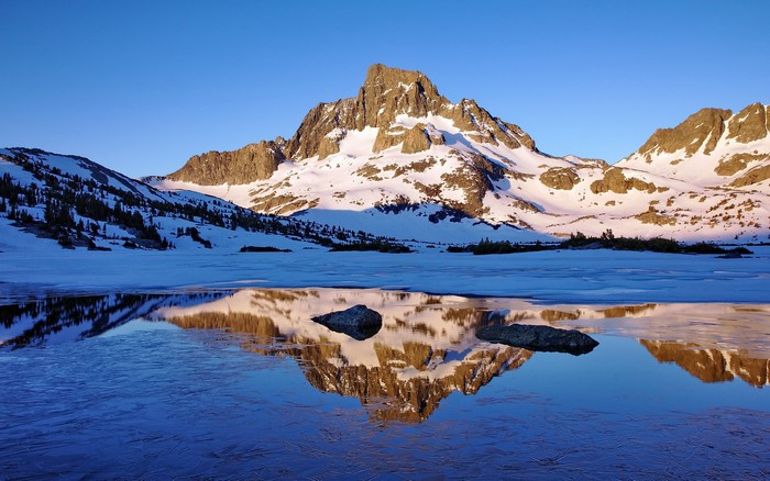 Snow-covered mountains reflected in a frozen lake