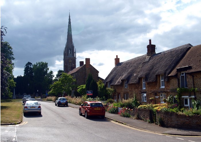 Village street with thatched cottages and church spire, United Kingdom
