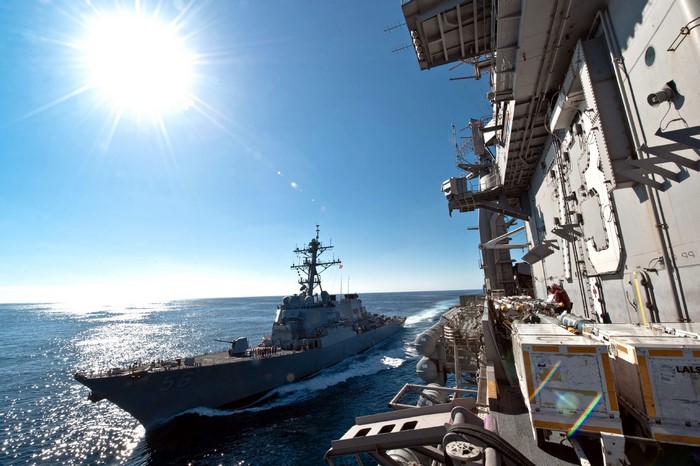 US Navy Destroyer sails alongside aircraft carrier
