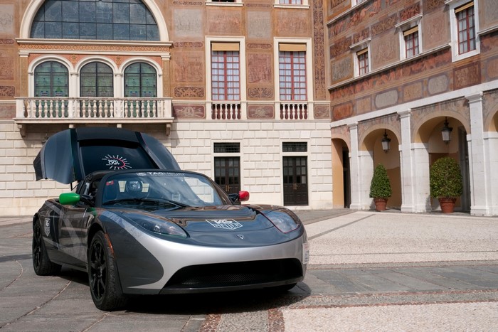 Tesla Roadster with open doors in front of a building