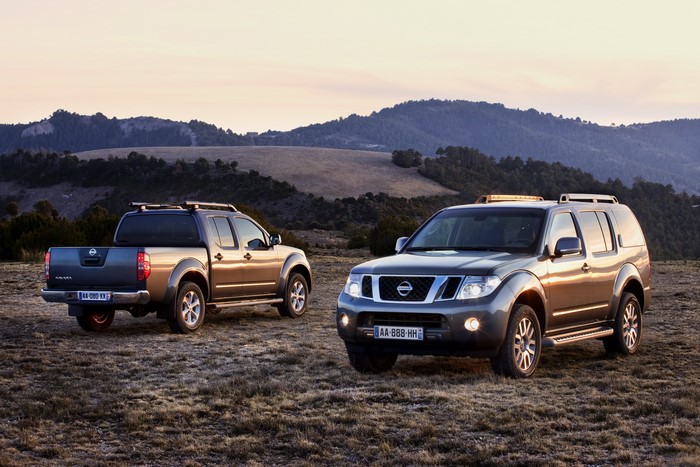 Two Nissan SUVs and Pickup Truck in a Field