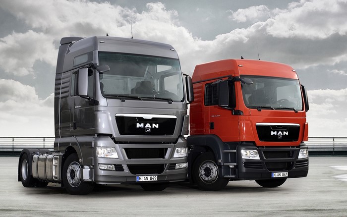 Two MAN SE trucks, one gray and one orange