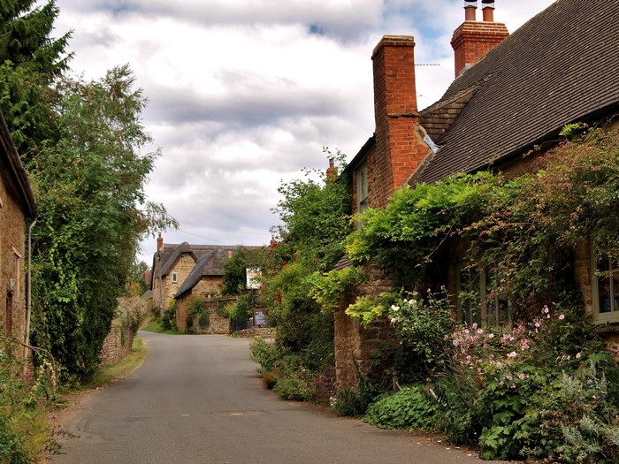 Quaint English village street with stone cottages and greenery