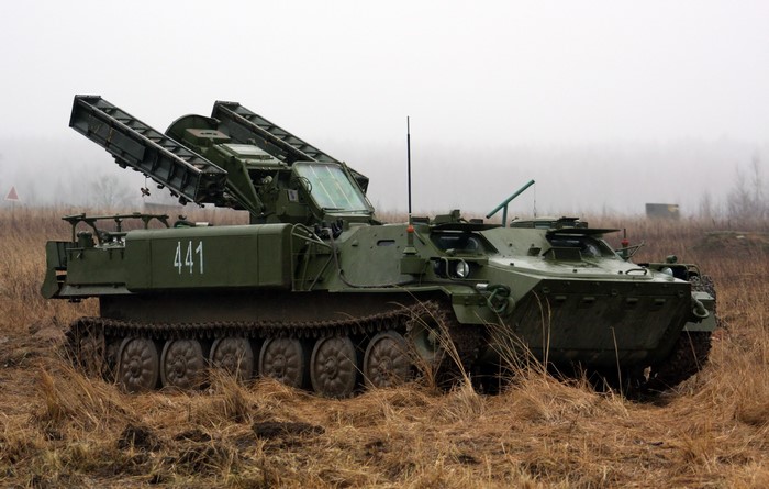 Green military vehicle with rocket launchers in a field