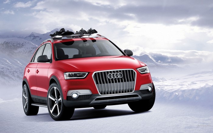 Red Audi Q3 with skis on roof rack in snow