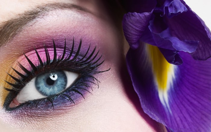 Close-up of a blue eye with colorful eyeshadow and a purple iris