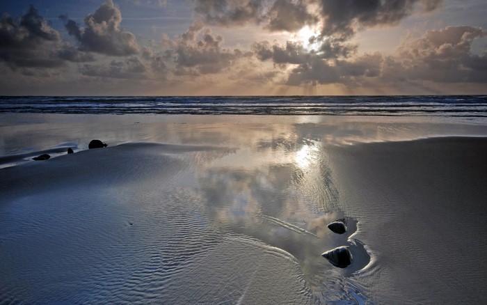 Beach with ocean waves and cloudy sky at sunset