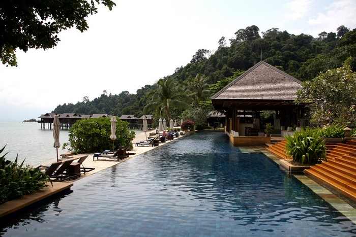 Infinity pool at a tropical resort with overwater bungalows