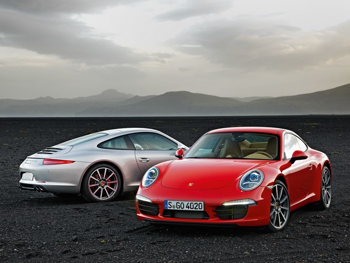 Two Porsche 911 cars on a dark landscape