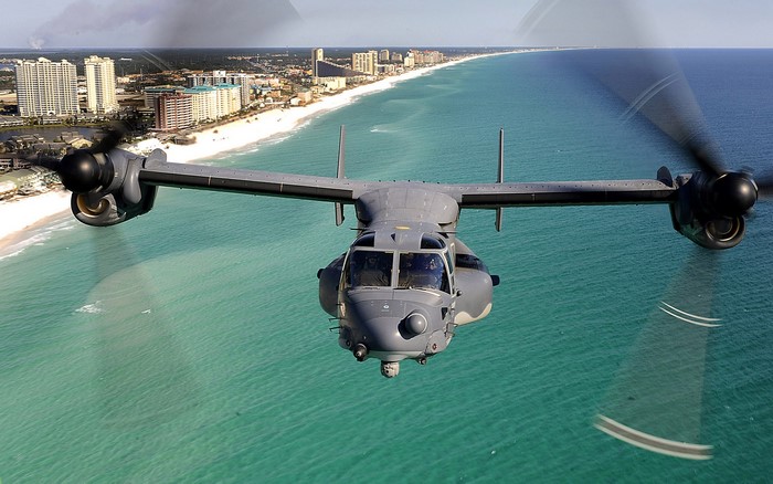 Bell Boeing V-22 Osprey flying over a beach city
