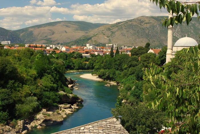 River flowing through a town with a mosque and mountains