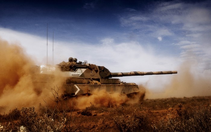 Tank moving through dust and brush