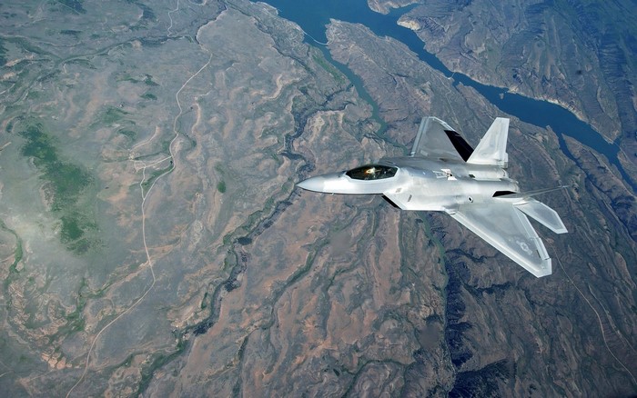 F-22 Raptor fighter jet flying over a canyon