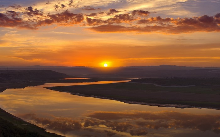 Sunset over a winding river with colorful clouds