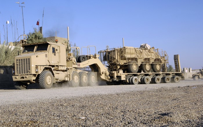 Oshkosh military truck transporting vehicles
