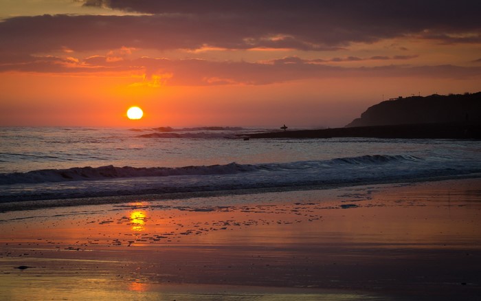 Sunset over the ocean with a surfer